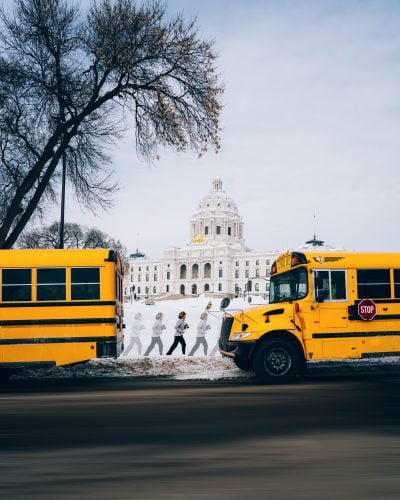 Two yellow buses parked near white building